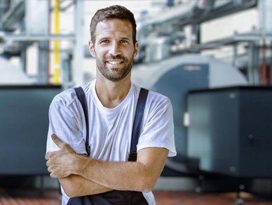 Ein lächelnder Mann in Arbeitskleidung mit verschänkten Armen